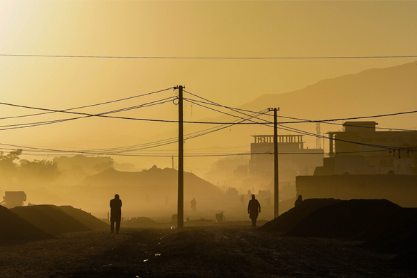 People walking down a street with wires strung above in the early morning