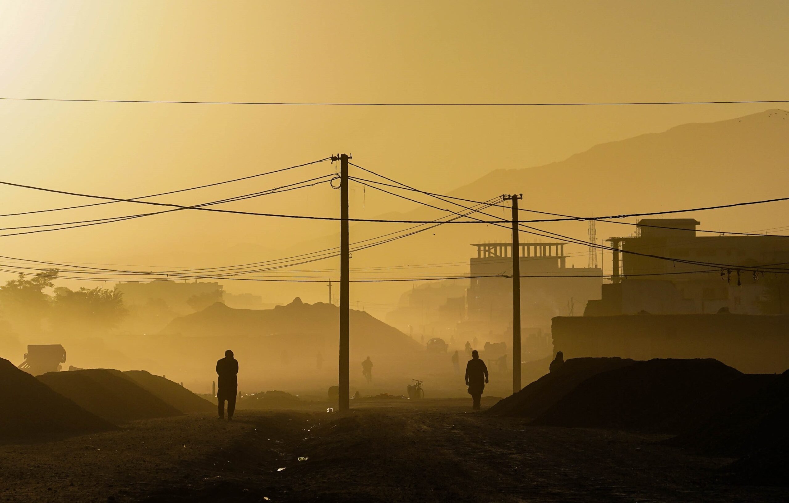 People walking down a street with wires strung above in the early morning