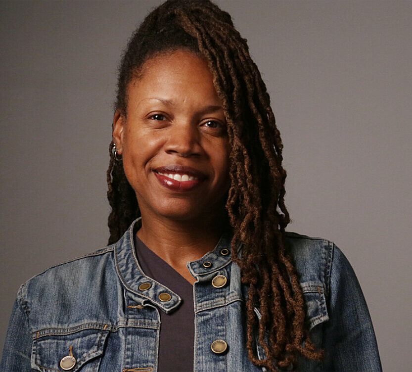 Natalie Bullock Brown, a dark skinned woman with long hair, wearing a denim jacket