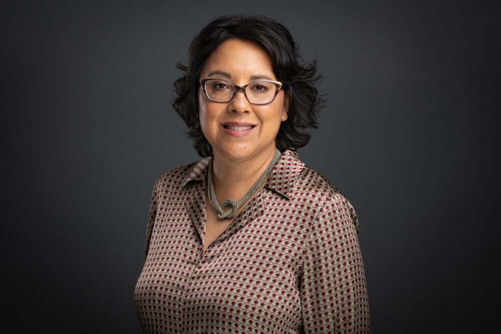 Photograph of a person wearing glasses and a necklace