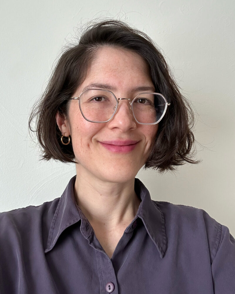 Sydney Tanigawa, a woman with light skin and chin length dark hair, wearing glasses and a collared shirt
