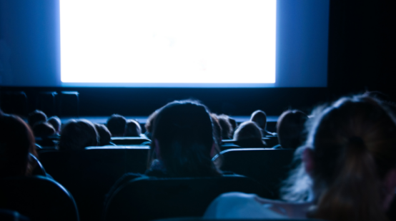Image of an audience looking toward a bright empty screen