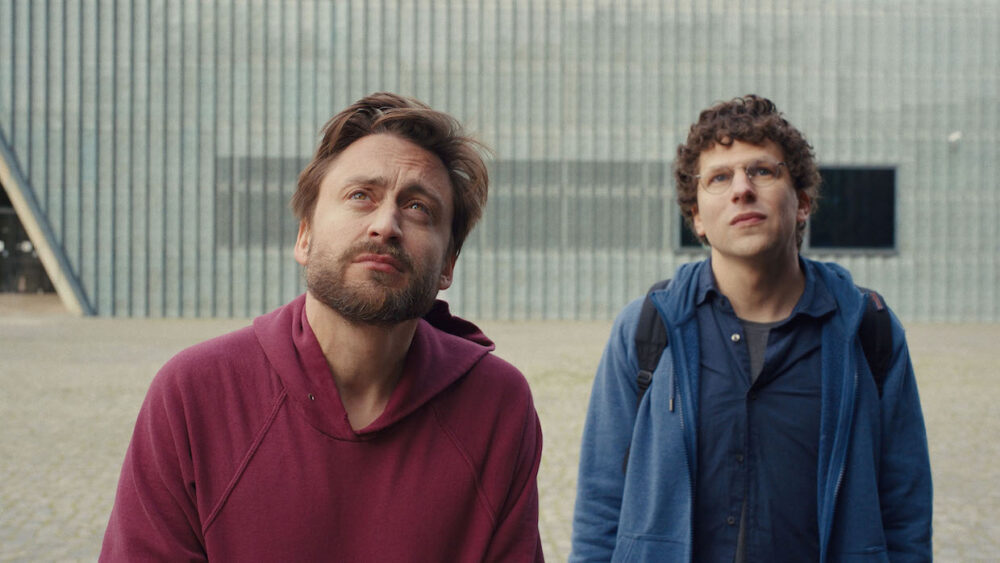 Photograph of two people wearing sweatshirts looking upward