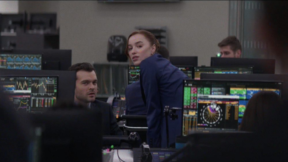 Photograph of two people looking into the camera amidst many computer screens in an office