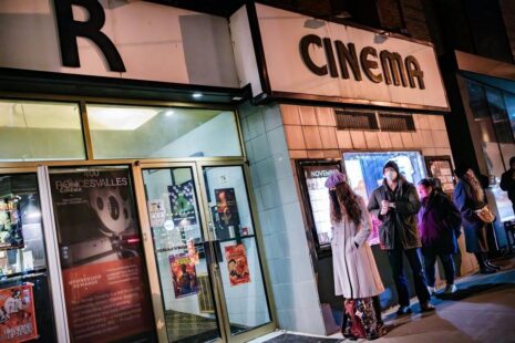 Photograph of people standing outside a cinema entrance