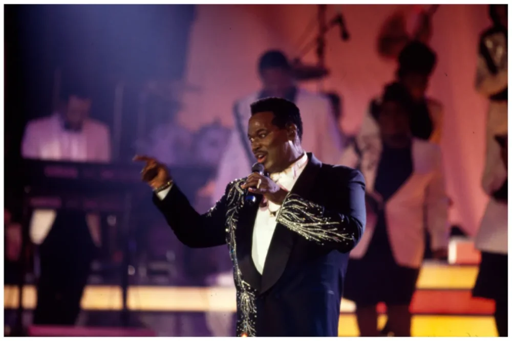A film still depicting a person singing on a stage