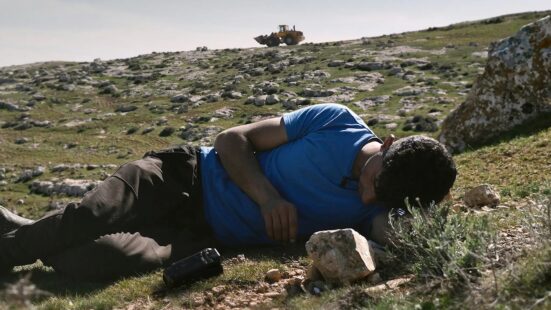 Still of a man on the ground from the film "No Other Land"