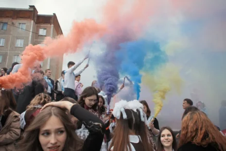 A lively group of individuals in a crowd releasing colorful smoke bombs.