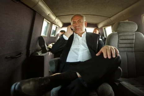 Man seated in a suit on the phone with a focused expression
