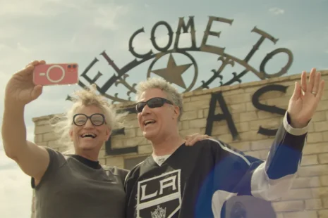 Two individuals smiling and taking a selfie in front of a Welcome to Texas sign