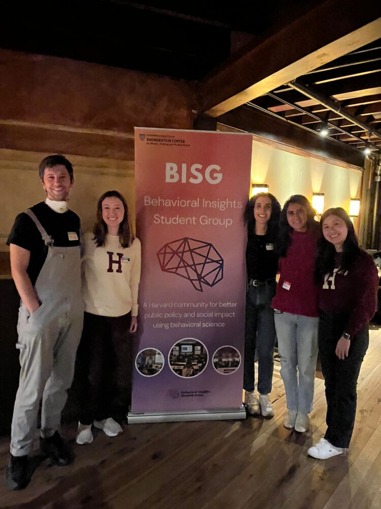 five student leaders stand around a Behavioral Insights Student Group banner