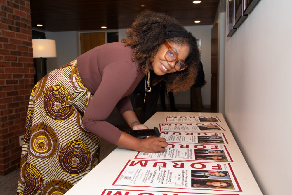 Brandi Collins-Dexter signs posters in the JFK Jr. Forum greenroom