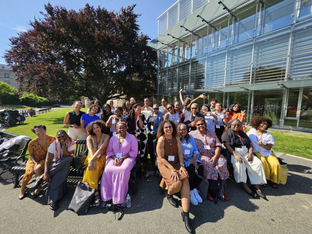 A group of attendees to the Outbraving Summit sit outside next to a glass-fronted building