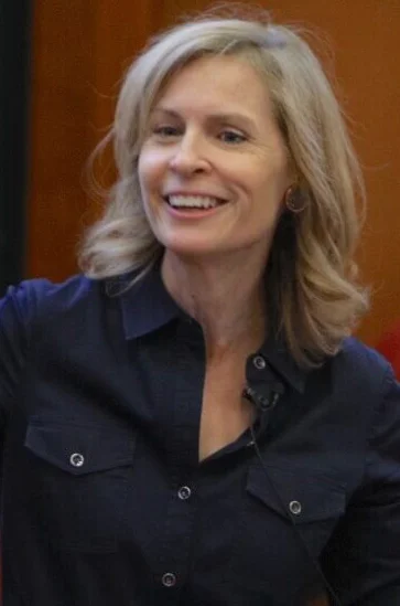 Susan Crawford, a light skinned woman with blonde hair, wearing a blue button down shirt