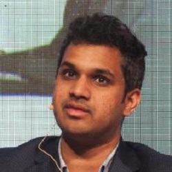 Arun Venkataraman, a medium skinned man with short dark hair, speaks on a stage.