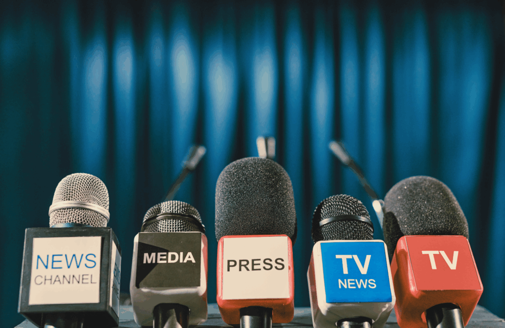 row of tv news mics at press conference with empty podium