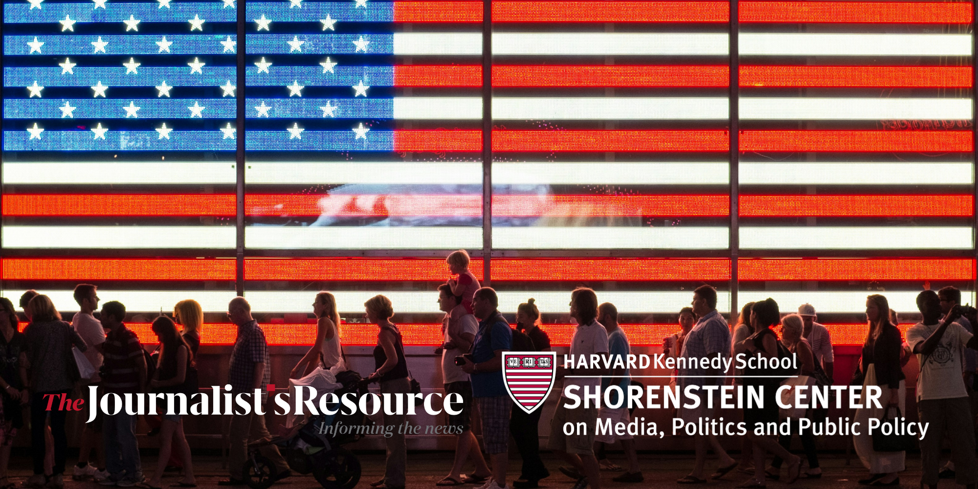 People walk in front of a large illuminated American flag, with logos for The Journalist’s Resource and the Shorenstein Center.