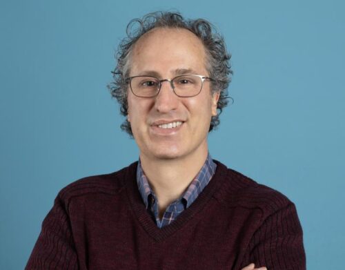 Professor Matthew Baum, a light skinned man wearing glasses and a collared shirt with sweater.