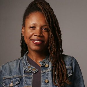 Natalie Bullock Brown, a dark skinned woman with long hair, wearing a denim jacket